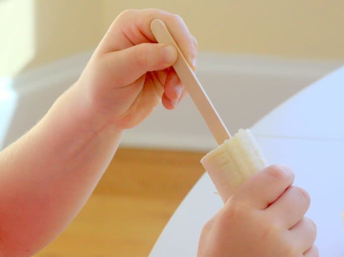 putting a stick in the banana for ghost pops